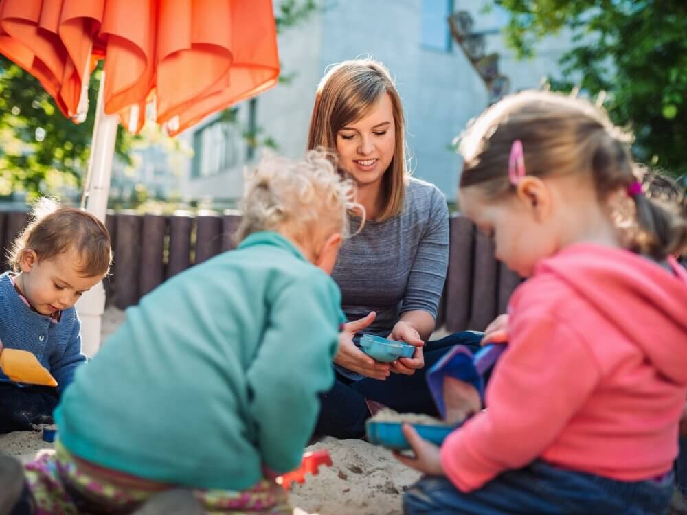 Eine junge Frau und zwei Kinder spielen draußen