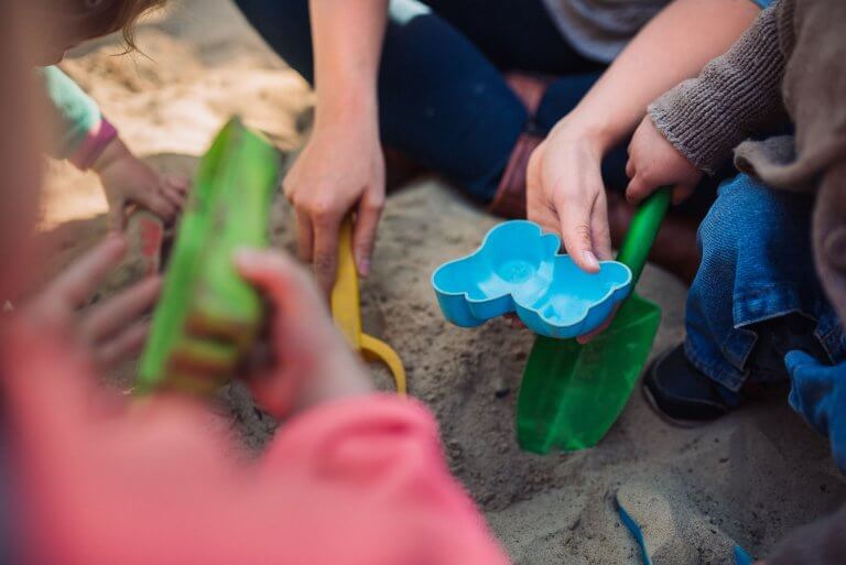 Kinderhände spielen mit Sandförmchen