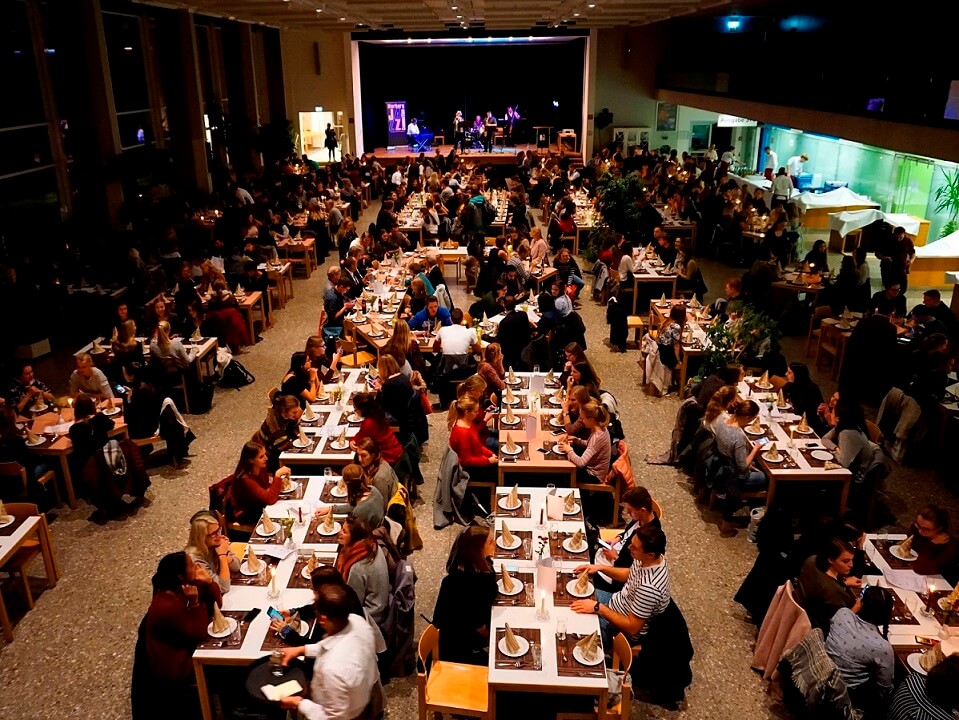 Wilkommensdinner im festlich geschmückten Speisesaal der Mensa Ansicht auf den voll besetzten Speisesaal bei Kerzenschein
